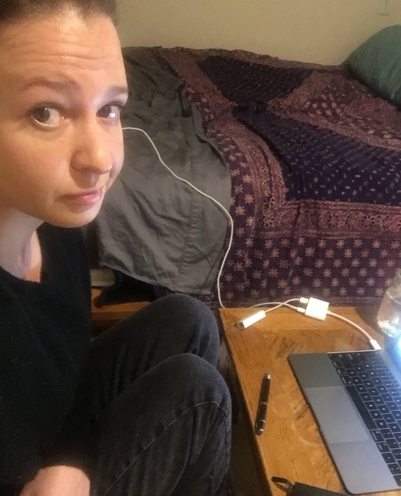 default-38 A woman poses for a selfie while sitting next to her laptop and bed.