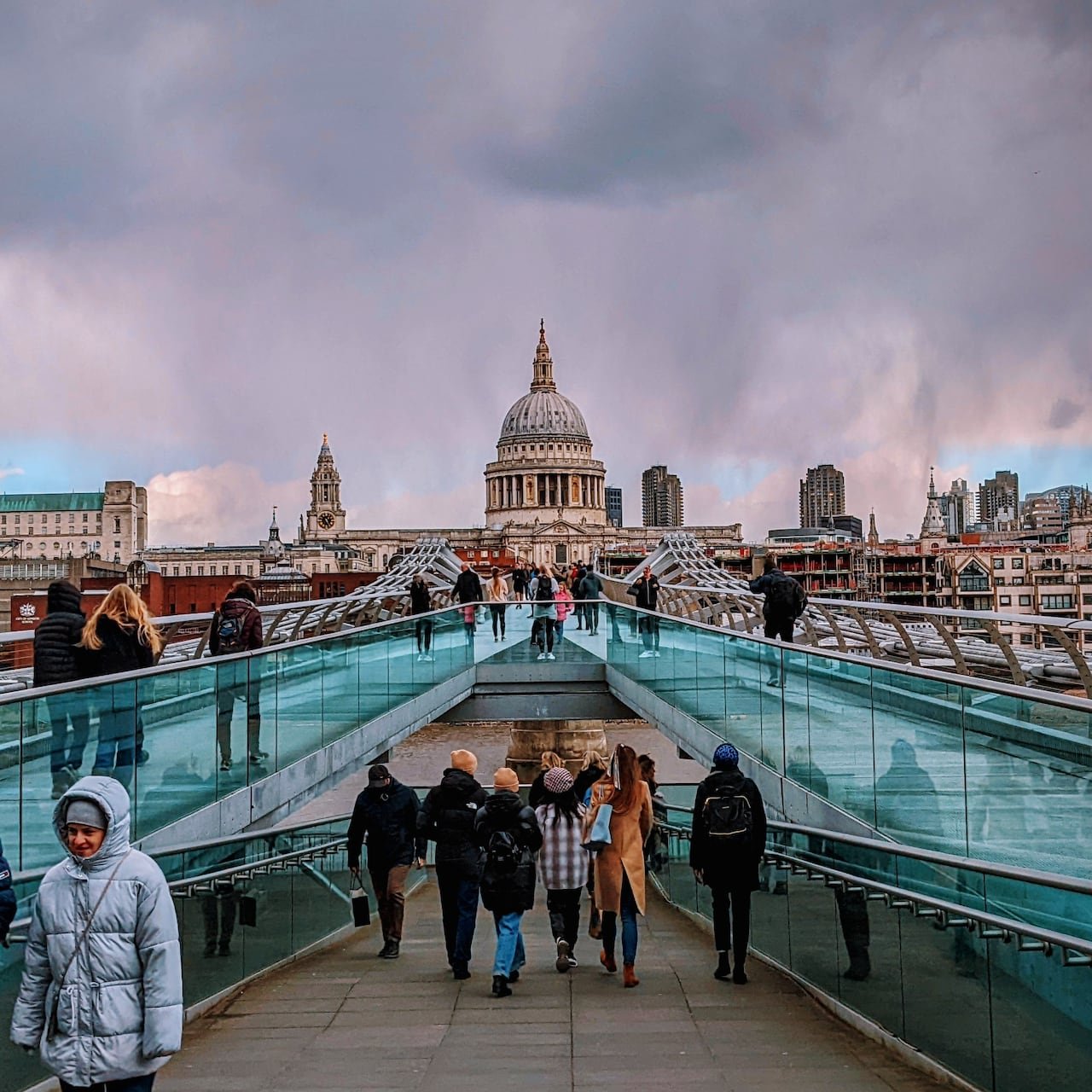 default-40 Crowds of people standing on a glass bridge leading to a large domed church.