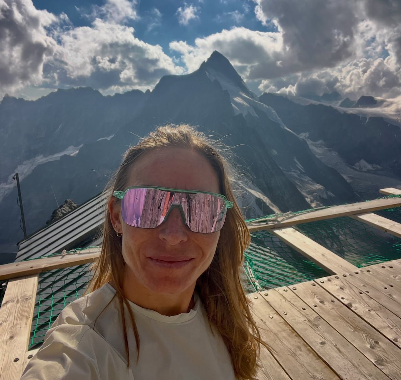 default-589 A woman wearing wraparound sunglasses is seen in front of a mountain.